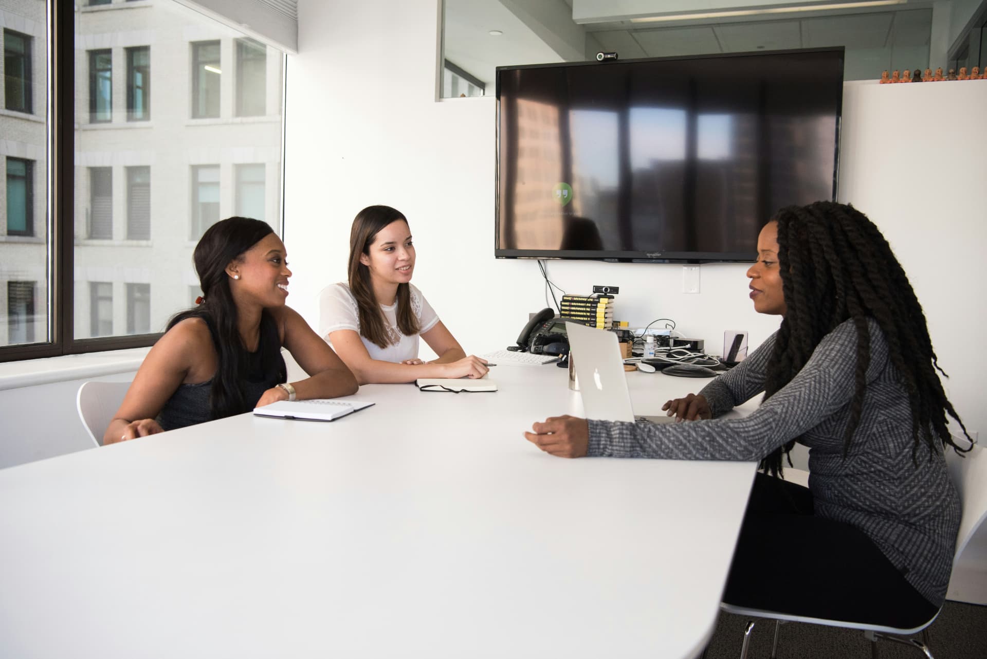 Three colleagues in a meeting room discussing hiring
